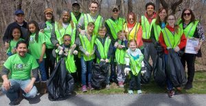 Volunteers wearing yellow vests collect trash near Doan Brook.